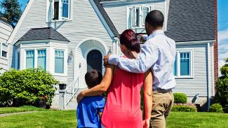 Family standing in front of a house and gazing at it